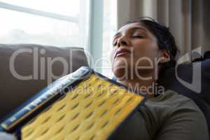 Woman with book sleeping on sofa