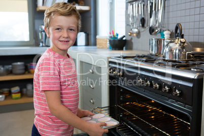 Portrait of boy holding muffin tin in kitchen