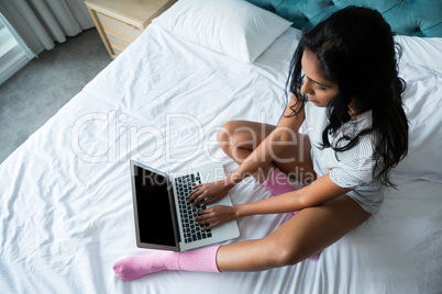 Full length of woman using laptop on bed