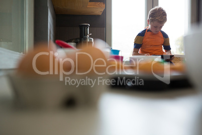 Boy using tablet at kitchen counter