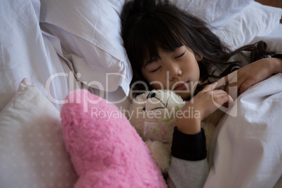 Girl with toys sleeping in bedroom