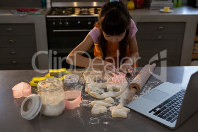 Girl making shape on dough in kitchen