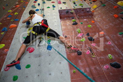 Woman practicing rock climbing in fitness studio