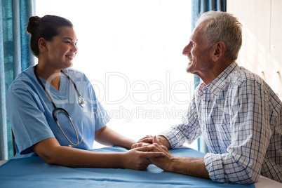 Smiling female doctor consoling senior man at table