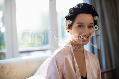 Beautiful bride with hair curlers on her head at home