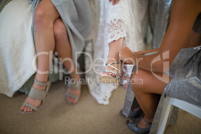 Bridesmaid helping bride to put on wedding shoes