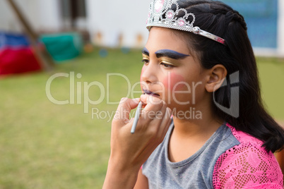 Cropped hand doing face paint on girl