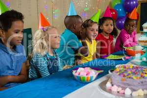 Boy whispering to girl while sitting with friends at table