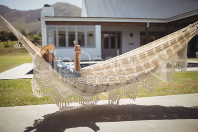 Senior woman using her mobile phone while relaxing in hammock