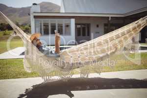 Senior woman using her mobile phone while relaxing in hammock