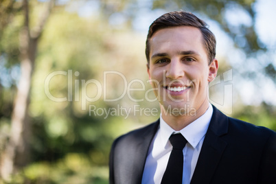 Happy groom standing in park