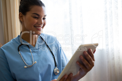 Smiling doctor using digital table in retirement home