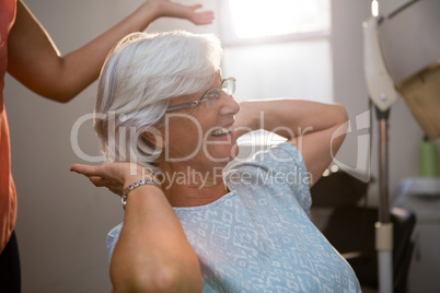 Midsection of hairstylist standing by happy senior woman