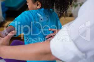 Physiotherapist examining girl patients back with goniometer
