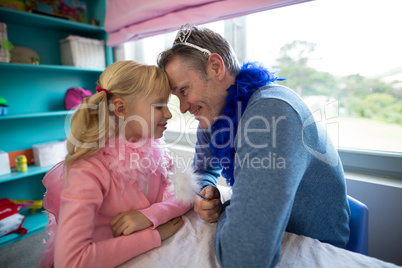 Girl and father dressed as fairy sitting head to head