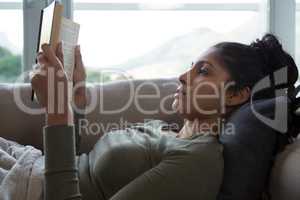 Young woman reading book on sofa