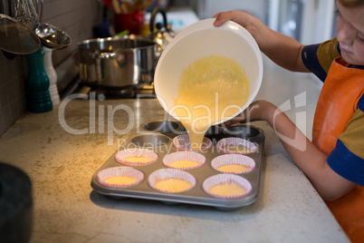 Boy pouring batter in cupcake holders