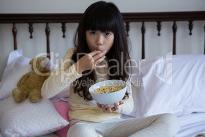 Portrait of girl eating breakfast on bed