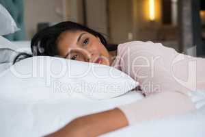 Thoughtful pretty woman relaxing on bed