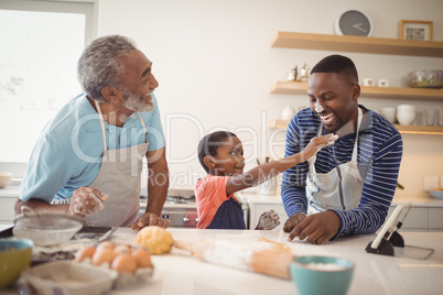 Multi-generation family with flour on the nose standing in the kitchen