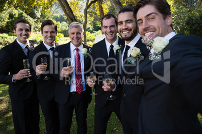 Portrait of groom and groomsmen having champagne