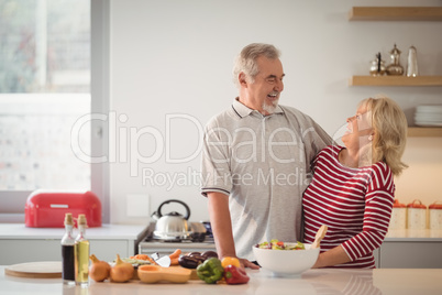 Senior couple embracing each other in kitchen