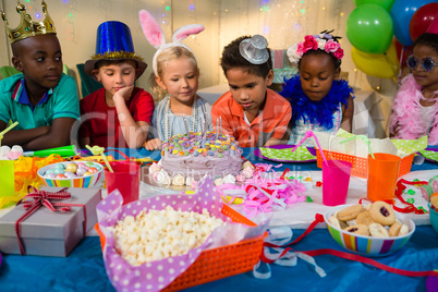 Children looking at birthday cake on table