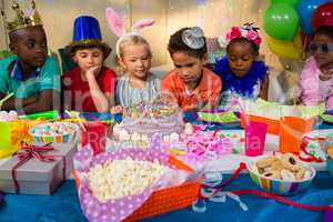 Children looking at birthday cake on table
