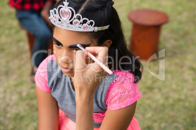 Cropped hand on mother applying face paint on girl wearing crown