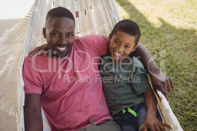 Smiling father and son relaxing on a hammock