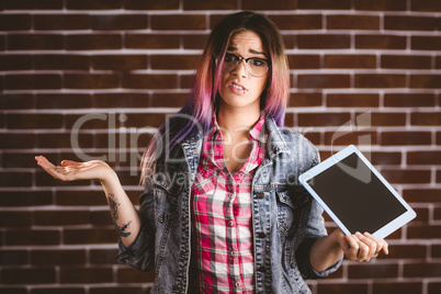 Portrait of confused woman holding digital tablet