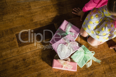Girl sitting with gift boxes on wooden floor