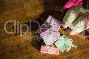 Girl sitting with gift boxes on wooden floor