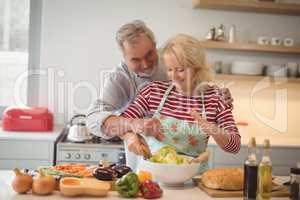 Senior couple mixing vegetables salad in bowl