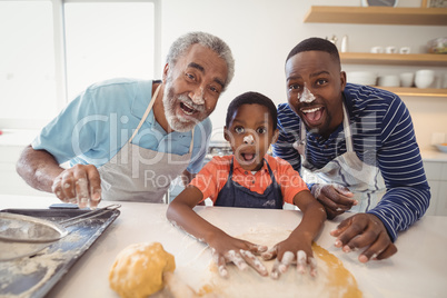 Multi-generation family with flour on the nose standing in the kitchen