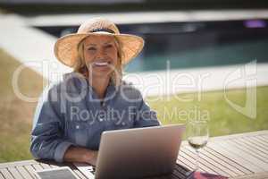 Senior woman using her laptop in lawn on a sunny day