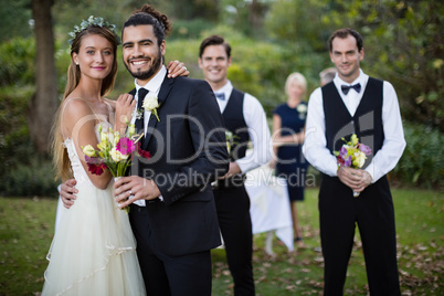 Wedding couple standing with bouquet of flowers in garden