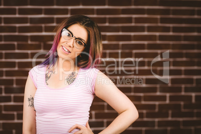 Smiling woman standing with hand on hip against brick wall