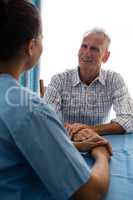 Man talking to female doctor at table in retirement home
