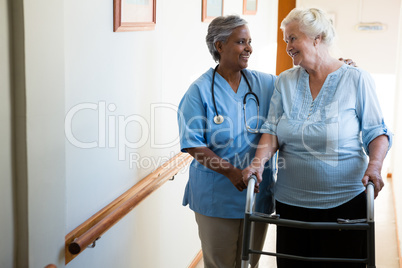 Nurse assisting patient in walking with walker at retirement home