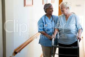 Nurse assisting patient in walking with walker at retirement home