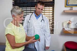 Physiotherapist assisting senior woman with stress ball exercise