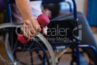 Senior woman in wheelchair performing exercise with dumbbell