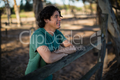 Man leaning on wooden fence in the ranch