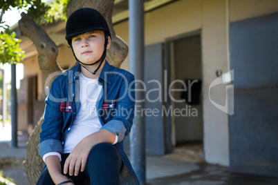Girl sitting on tree trunk near stable