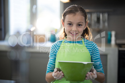 Smiling girl holding a bowl in the kitchen