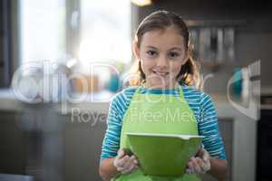 Smiling girl holding a bowl in the kitchen