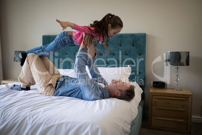 Happy father and daughter having fun on bed in bedroom