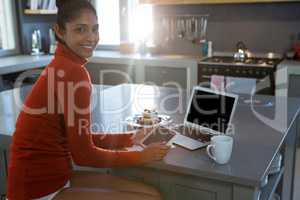 Portrait of smiling woman using tablet in kitchen