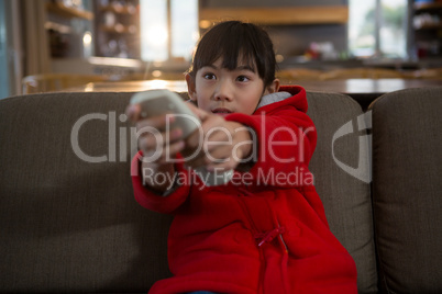 Girl using remote control while sitting on sofa